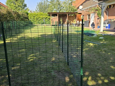 Erste Ecke eines Katzengeheges mit grünen Gitterelementen im Garten