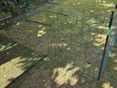 Aufbau eines Katzengeheges im Garten mit aufgestellten grünen Gitterelementen