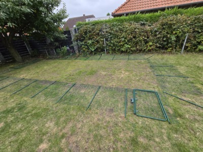 Ausgelegte Gitterelemente und Türrahmen für ein Katzengehege auf dem Rasen