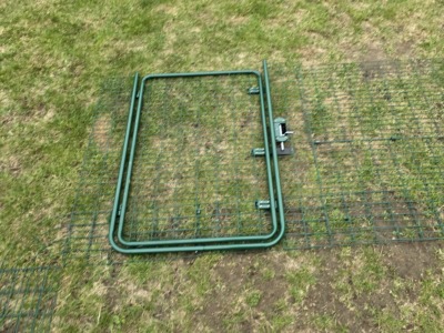 Türelement mit Verschluss für ein Katzengehege liegt auf dem Rasen bereit