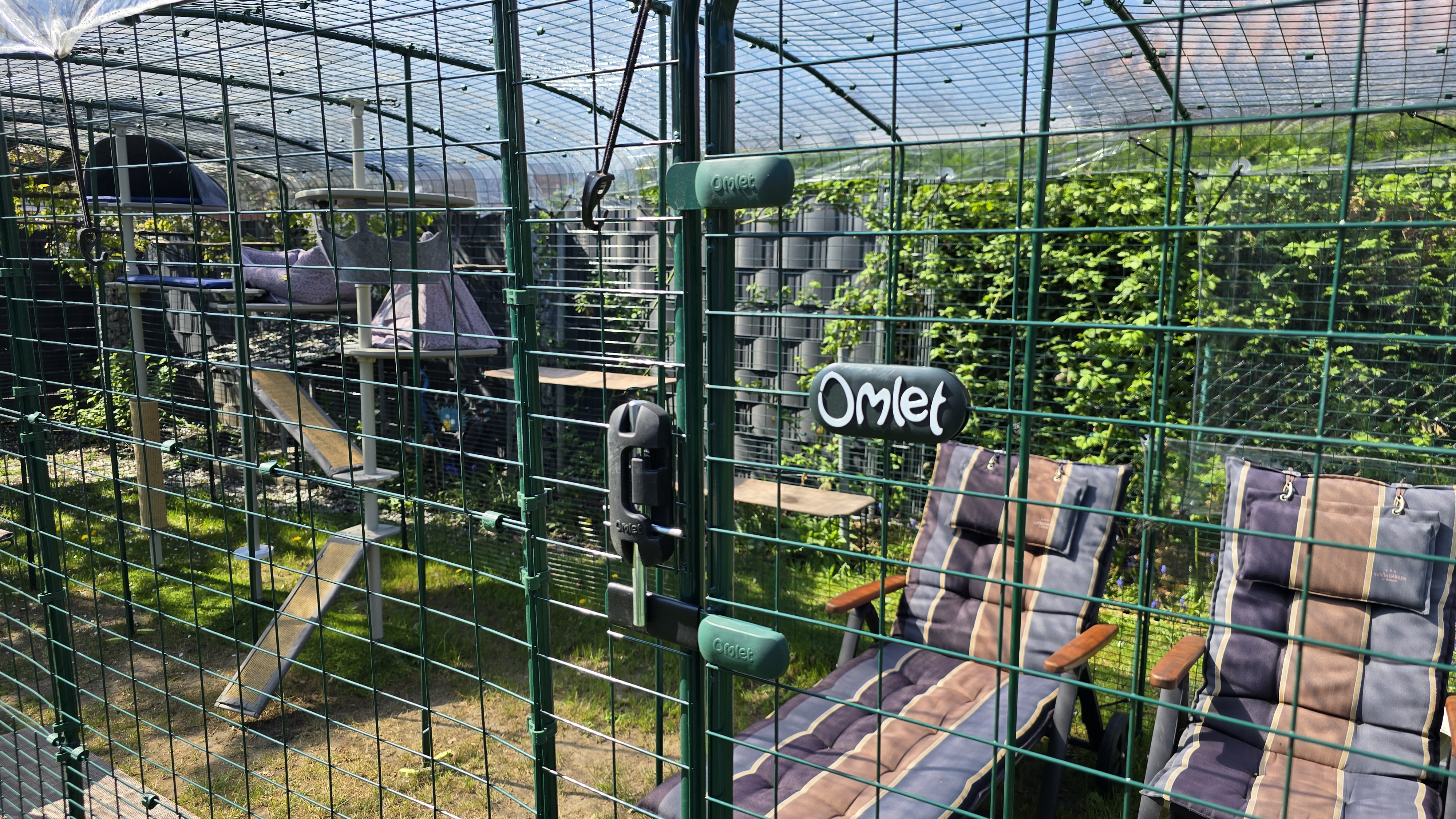 Sitzecke im Omlet Katzengehege mit Liege und Stuhl am Eingang, katzensicher eingezäunt